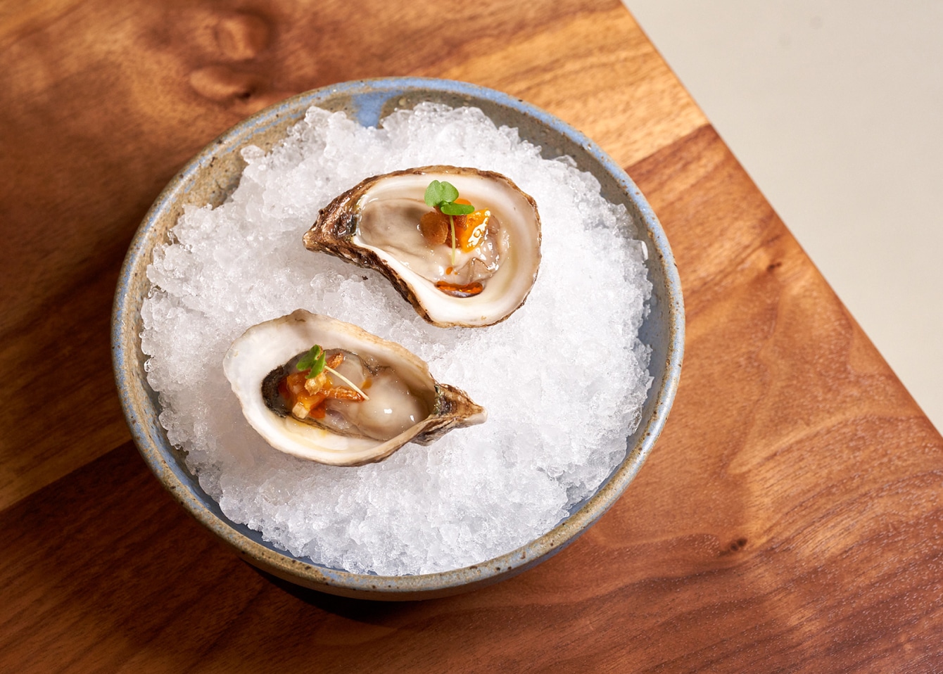 Oysters served on ice in an earthen bowl.