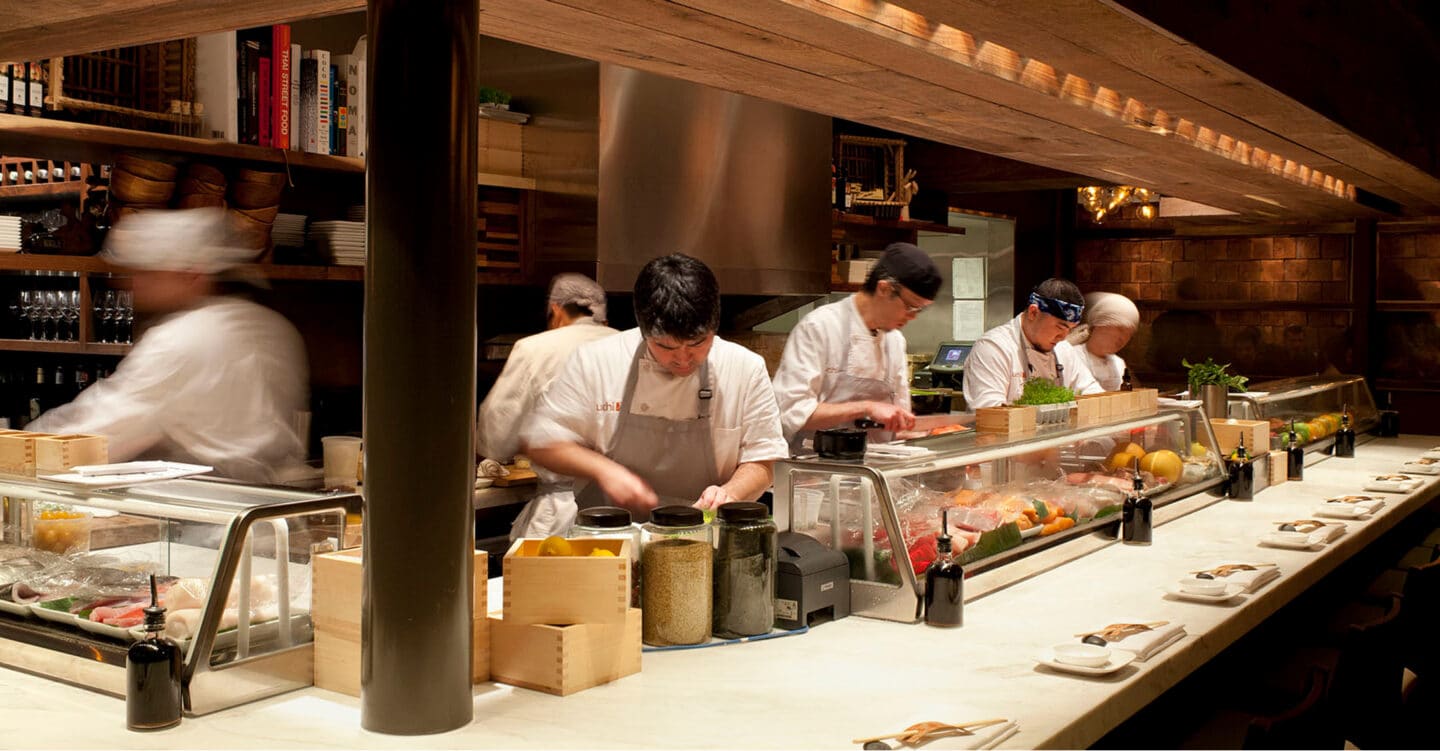 A team of chefs working behind the sushi bar at Uchi Houston.