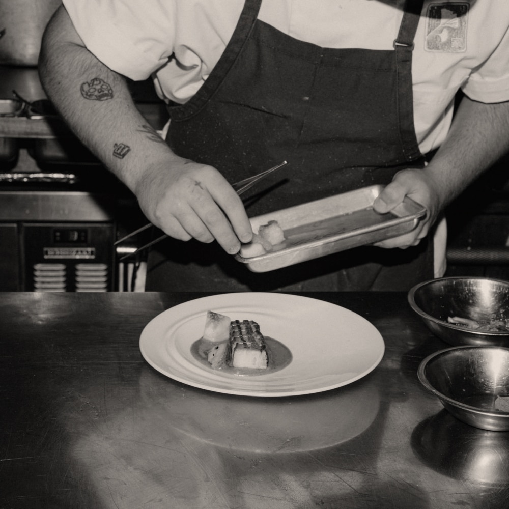 A close-up of a chef plating a meal.