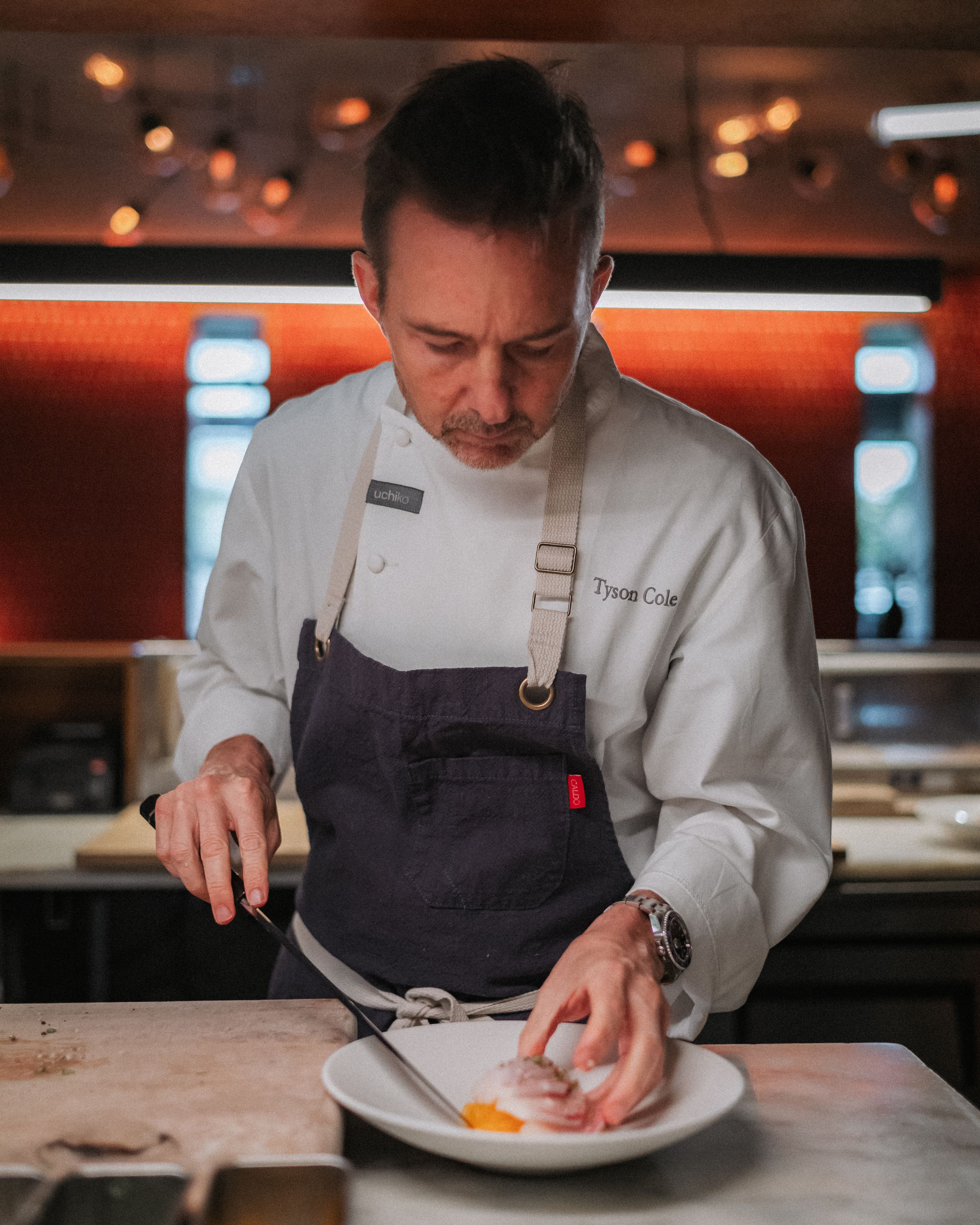 photo of chef tyson cole plating a dish at uchi